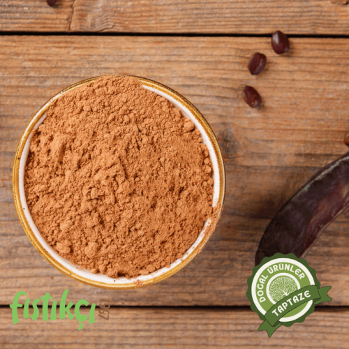 Bir kasede taze keçiboynuzu unu ve yanında meyvesi